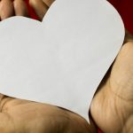 a person holding a paper heart in their hands